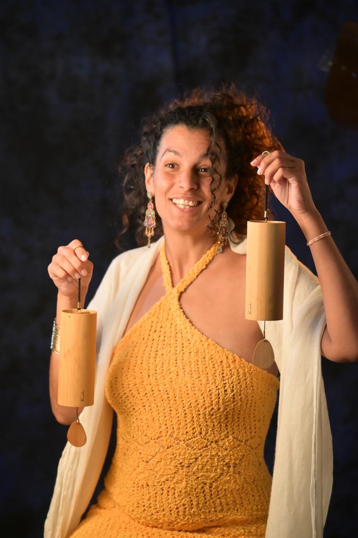 Maïya smiling, holding two bamboo chimes